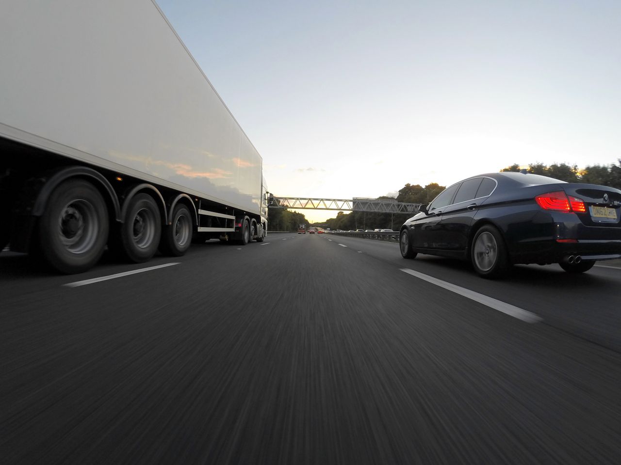 Services Cars and a truck speed along a highway under the clear sky, showcasing transportation dynamics.