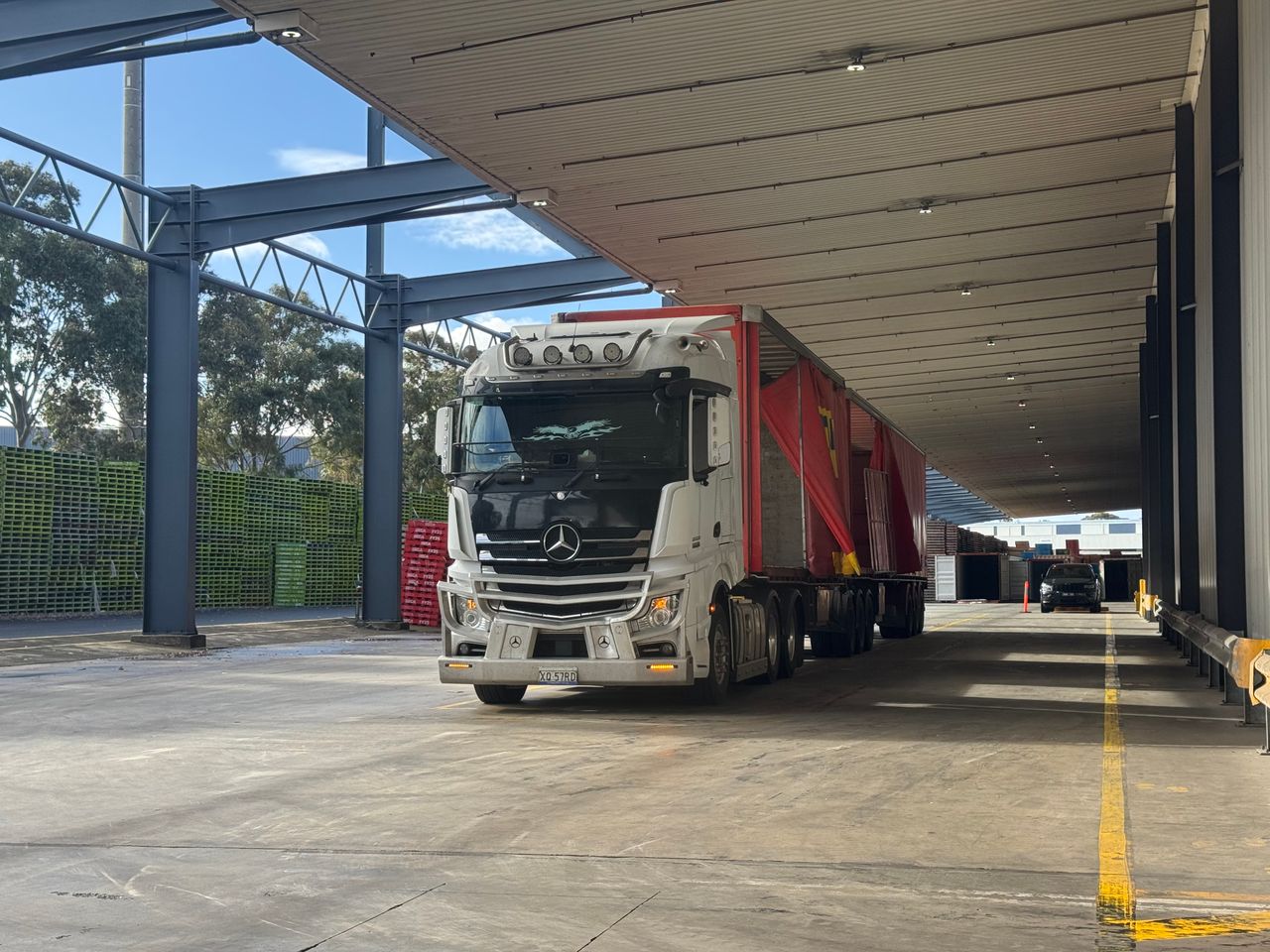 About Large truck parked in a loading bay under a roof, ready for industrial transport.