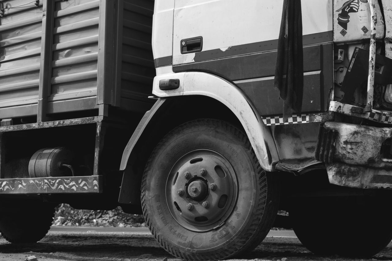 Services Monochrome close-up of a rugged industrial truck wheel and body detail.